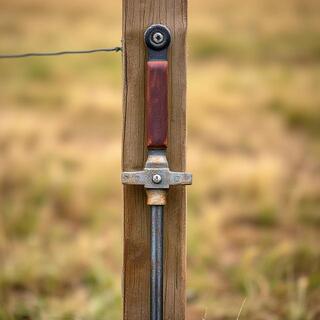 Manual post driver leaning on a fence